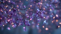 Delicate purple flowers on dark branches with warm glowing lights creating magical bokeh effect for romantic spring decoration and festive atmosphere.
