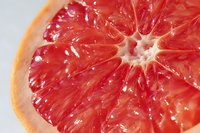 Fresh grapefruit half showing juicy red pulp segments and natural citrus texture on white background for healthy eating and nutrition concepts.