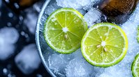 Refreshing cocktail with lime slices and ice cubes in glass, cold beverage for summer parties and bar service.