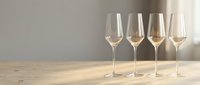 Four elegant champagne flutes arranged on wooden surface with soft natural lighting creating warm ambiance for celebration or fine dining.