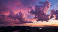 Dramatic purple and pink sunset sky with fluffy clouds over mountain landscape. Vibrant twilight colors create stunning natural backdrop for travel content.