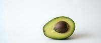 Fresh ripe avocado half with pit on clean white background. Healthy organic fruit ingredient for cooking, nutrition and wellness lifestyle.