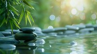 Tranquil spa composition with black massage stones and bamboo leaves reflecting in calm water surface, perfect for wellness and meditation background with soft bokeh effect.