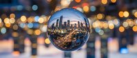 Cityscape reflected in crystal sphere with bokeh lights, urban skyline at dusk, downtown architecture, evening illumination, business district overview.
