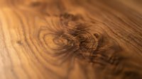 Close-up of wood grain texture showing natural knots and swirling patterns in warm brown tones, suitable for backgrounds and design projects.