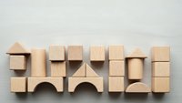 Natural wooden building blocks arranged in rows on neutral background for educational play and creative construction activities.
