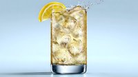 Refreshing glass of iced tea with lemon slice garnish and ice cubes against light blue background, splashing liquid creating dynamic movement.