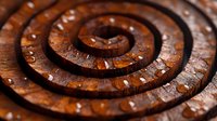 Mesmerizing spiral pattern carved in rich brown wood with scattered water droplets creating dramatic texture and depth. Natural organic design for backgrounds.