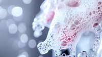 Close-up of soap foam bubbles with pink and blue tones creating abstract texture for cleaning and hygiene concepts in commercial photography.