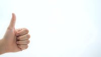 Hand showing thumbs up gesture against white background expressing approval, success and positive feedback for business presentations.