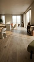 Modern minimalist living room with natural wood flooring, large windows, neutral furniture and warm lighting creating cozy residential interior space.