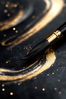 Black paintbrush with gold ferrule creates elegant strokes on dark surface with scattered golden glitter and paint swirls, capturing artistic creativity in macro.