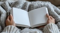 Person holding open blank book with cozy knit sweater, reading or writing concept for education, literature, journaling, and creative projects.