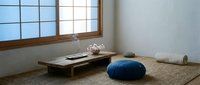 Minimalist Japanese meditation room with tatami mats, low wooden table, blue cushion and traditional shoji screen windows for zen interior design.