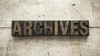 Vintage wooden letterpress blocks spelling ARCHIVES on weathered wood background for historical documentation and record keeping projects.