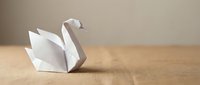 White origami swan folded from paper resting on a craft surface, showcasing the art of paper folding with minimalist elegance.