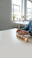 Person arranging wooden question mark blocks on white desk in bright modern office workspace for business problem solving and decision making concepts.