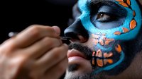 Close up of face art makeup in turquoise and orange butterfly pattern on dark skin male model, professional cosmetic application process showing artistic detail.