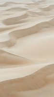 Aerial view of undulating sand dunes with smooth, flowing curves and rippled textures in warm beige and cream tones. Suitable for travel, nature, and desert-themed designs.