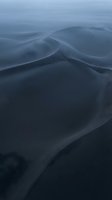 Smooth flowing blue fabric waves creating elegant curves and shadows in soft lighting for luxury textile and fashion design backgrounds.