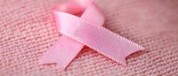 Pink awareness ribbon on soft pink textile background symbolizing breast cancer support and women's health advocacy movement for medical awareness campaigns.