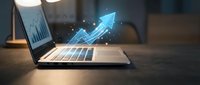 Digital growth arrow emerging from laptop screen with glowing particles showing business success and financial progress in modern office environment.