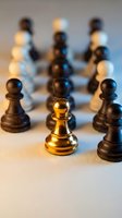 Golden chess pawn stands out among black pieces on board with dramatic lighting for business strategy and leadership concepts.