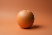 Fresh grapefruit on a warm terracotta background, showcasing its textured peel and round shape for food and healthy lifestyle concepts.
