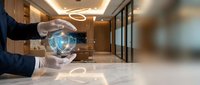 Businessman hands protecting digital security shield icon in modern office lobby representing cybersecurity data protection and business safety concepts.