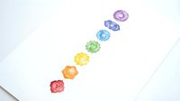 Colorful gemstones arranged in diagonal line representing chakra energy centers, isolated on white background for design, wellness graphics, and spiritual artwork projects.