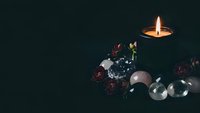 Mystical fortune telling setup with candle flame, crystal balls, dried roses and dark atmospheric lighting for spiritual divination practices.