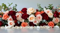 Romantic floral arrangement featuring burgundy, coral and blush roses with delicate eucalyptus greenery against light background, suitable for wedding and event decor.