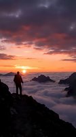 Hiker standing on rocky mountain peak watching golden sunrise over sea of clouds and distant peaks at dawn.