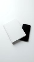 Minimalist white notebook and black smartphone on clean white background for business planning and digital productivity workspace mockup.