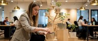 Young professional businesswoman building wooden block tower in modern office workspace representing growth strategy and teamwork development.