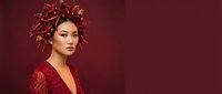 Woman with East Asian ethnicity wearing elaborate red sparkly headpiece and matching garment against burgundy background. Suitable for fashion, beauty, editorial, and holiday campaigns.