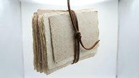Stack of natural linen fabric swatches tied with brown twine, showcasing textile samples for interior design, fashion, and home decor projects.