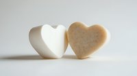 Two heart-shaped soap bars in white and beige colors on clean background for spa wellness skincare and romantic bath products.