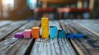 Colorful wooden blocks arranged as ascending and descending bar graph on rustic wooden table surface, demonstrating business analytics and data visualization concepts.