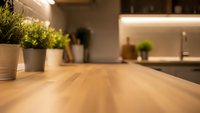 Modern kitchen interior with wooden countertop and blurred background featuring plants and warm lighting for home design and cooking concepts.
