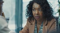 African American businesswoman with curly hair wearing beige blazer listening intently during office meeting, displaying professional engagement and leadership.