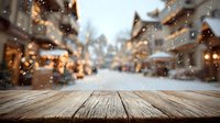 Rustic wooden table with blurred winter village street view in background, snow falling on cozy alpine chalets with warm lights.