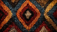 Vibrant knitted pattern with diamond shapes in autumn colors of orange, burgundy and teal creates cozy textile texture. Traditional folk design motif.