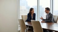 Professional business meeting with confident woman and man discussing strategy in modern conference room with city view for corporate presentations.