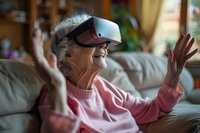 Senior Caucasian woman wearing VR headset, expressing joy and amazement while experiencing virtual reality at home, dressed in pink sweater on couch.