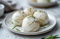 Japanese onigiri rice balls garnished with fresh herbs and nori seaweed strips on white ceramic plate, selective focus with soft natural lighting.