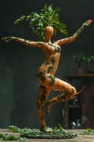 Creative food art composition featuring a dancing carrot figure sculpted to resemble a graceful ballet dancer, with natural foliage crown. Perfect for culinary blogs and healthy lifestyle content.