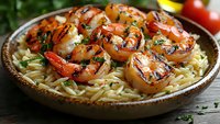 Grilled shrimp with herbs served over pasta in rustic ceramic bowl. Fresh seafood dinner with garlic and seasonings on wooden table for restaurant menu.