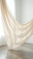 Flowing beige linen curtain fabric draped elegantly in minimalist white interior room with natural light and concrete floor for home decor design.
