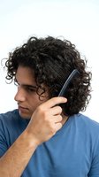 Young man with dark curly hair and olive complexion combing hair with blue comb against white background for grooming and hair care product advertising.